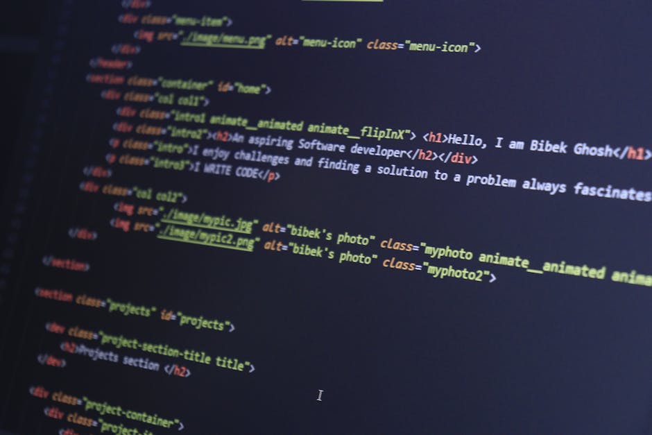 A photograph of a computer screen displaying lines of HTML code in a dark-themed editor. The code features colorful syntax highlighting with tags such as <h1> and <div>, attributes like 'class' and 'a